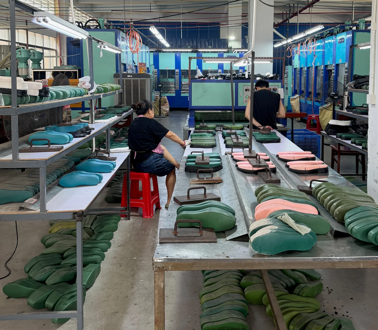 Operators working with sole shaping forms beside EVA production equipment.