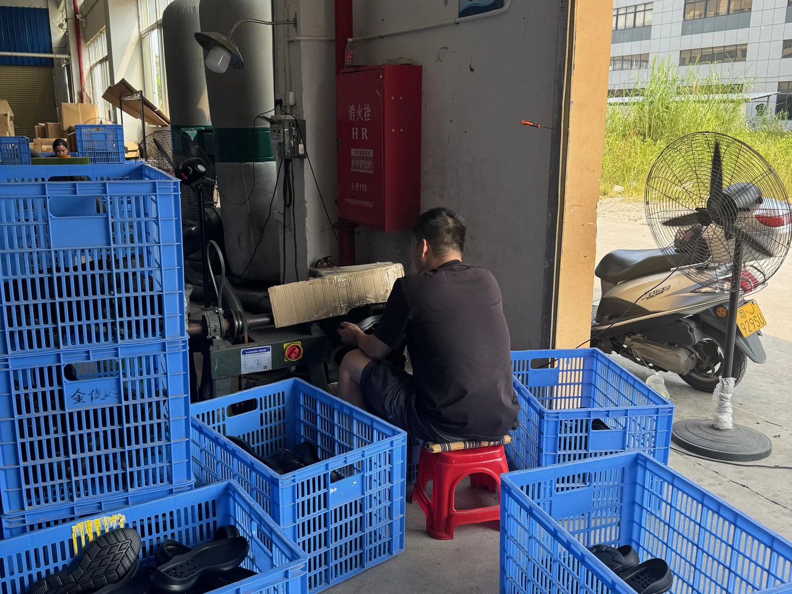 Worker roughing sole surfaces at a factory workstation.